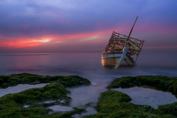 Verlassenes Schiff im Meer bei Sonnenuntergang