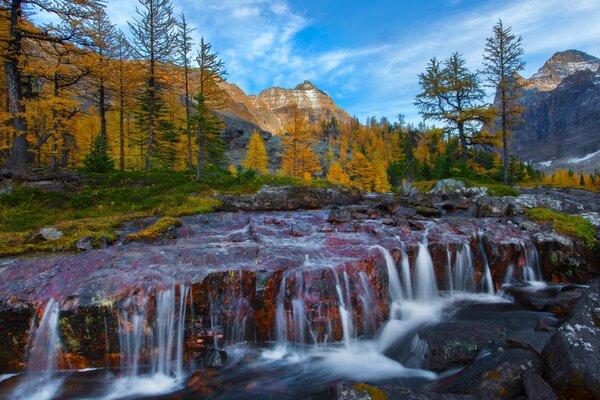 Hier ist alles liebkost: ein Wasserfall, ein Fluss und Steine und natürlich Berge