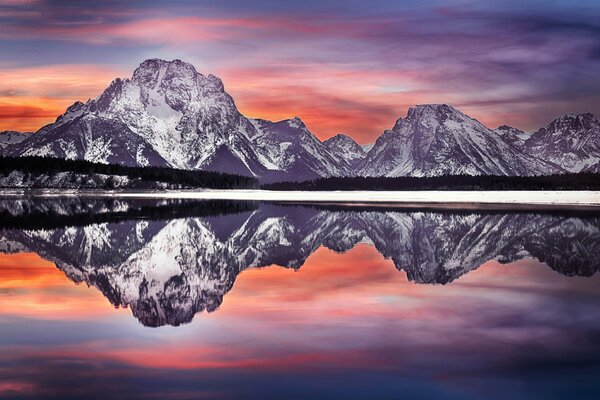 Die erstaunlichen Farben der untergehenden Sonne spiegeln sich im Wasser am Fuße der Berge im Grand Teton National Park der USA wider