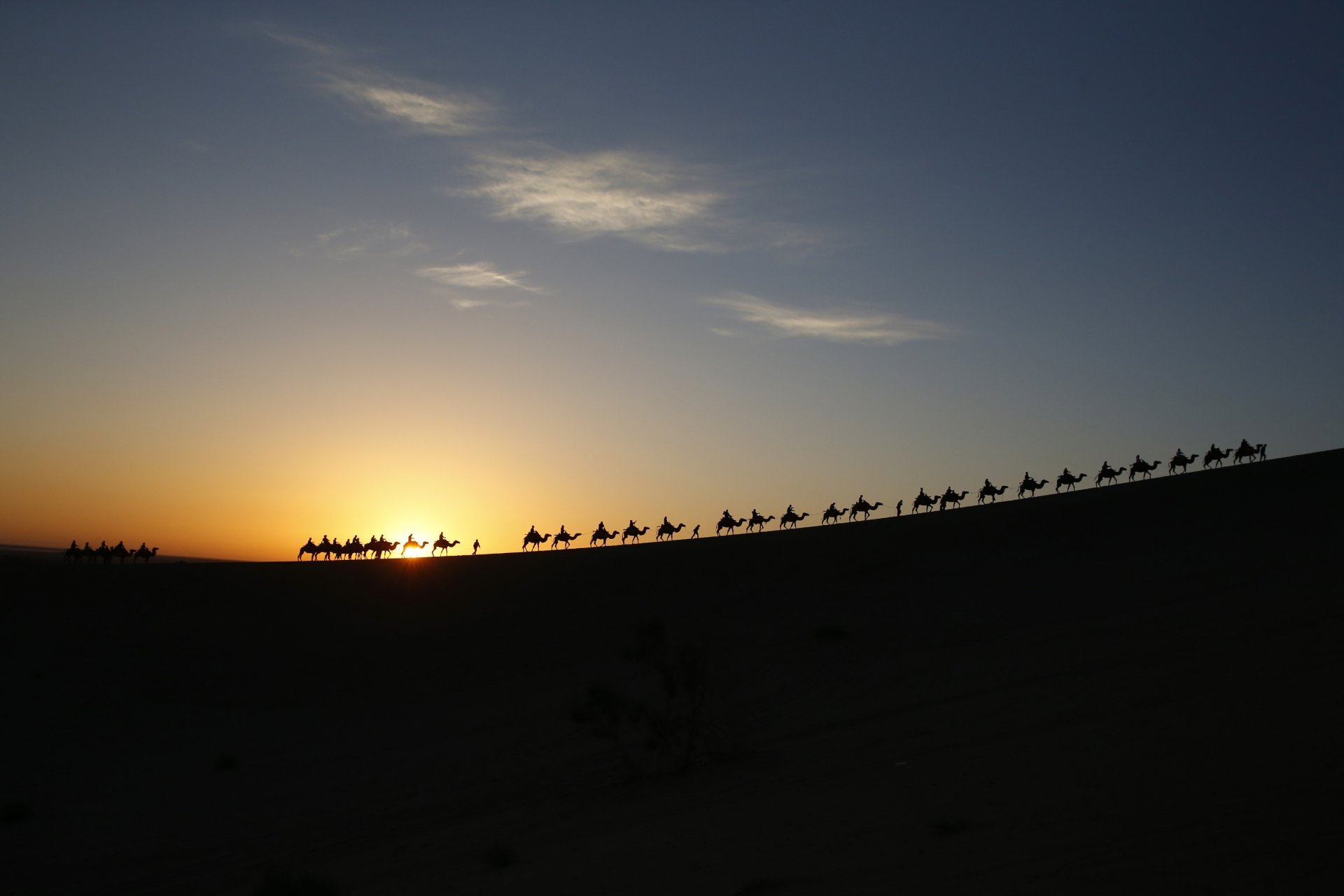 caravan camels people sun sky clouds desert