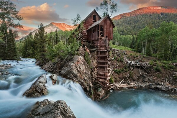 Molino de cristal rodeado de aguas profundas y bosques al atardecer