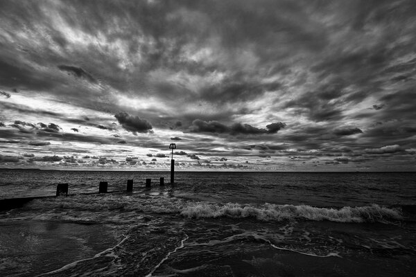 Black and white photo of the ocean under a cloudy sky