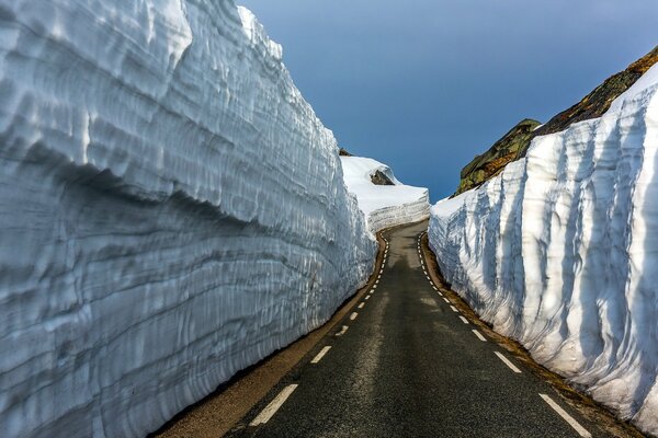 Strada che va in lontananza tra le rocce innevate di montagna