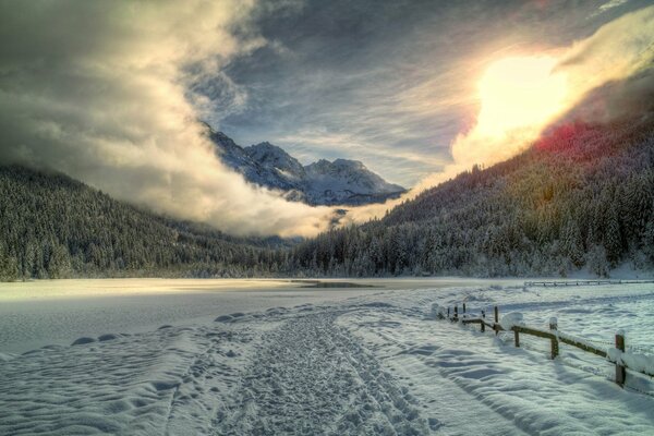 Verschneite Straße entlang eines mit Schnee bedeckten Sees