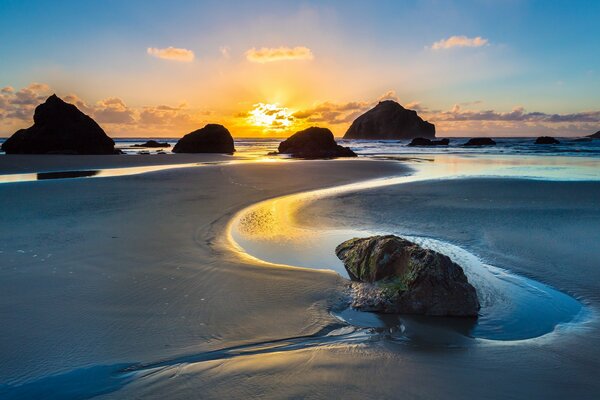 Sonnenaufgang am Strand hinter den Felsen