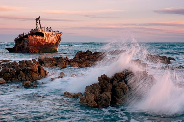 Nave tra il mare e le rocce sullo sfondo del tramonto