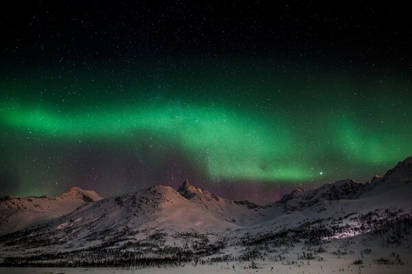 Aurora boreal en las laderas de las montañas en invierno