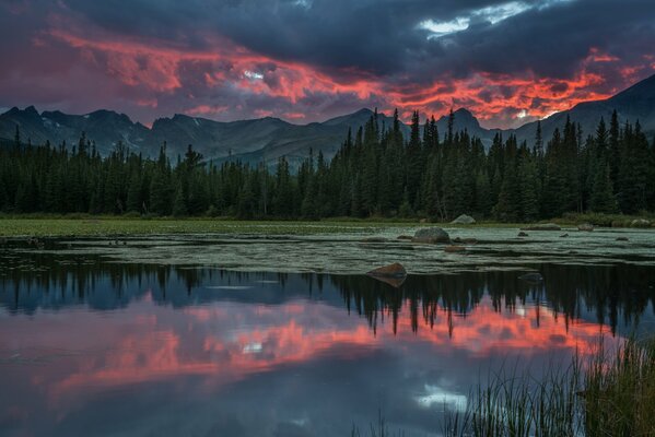 Reflection of clouds in the river against the background of mountains and forests