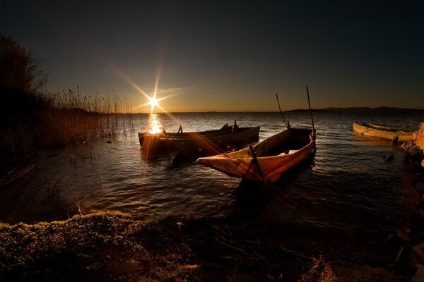 The sun illuminates the lake with three boats