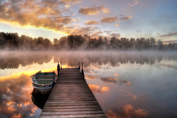 Puente y barco en el lago en la niebla de la mañana