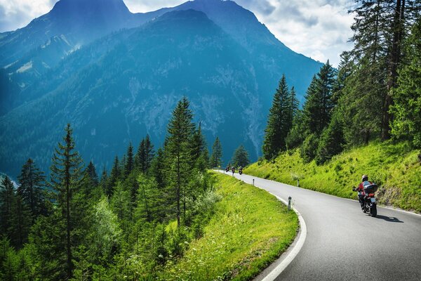 Motorradfahrer fährt auf einer Bergstraße inmitten der grünen Berge