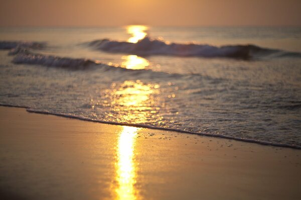 Al amanecer, las olas del mar reflejan los rayos del sol